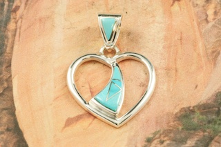 Genuine Sleeping Beauty Turquoise inlaid between ribbons of Sterling Silver. Beautiful inlay on the bale and pendant. Free 18" Sterling Silver Chain with purchase of pendant. Designed by Navajo Artist Calvin Begay. Signed by the artist.